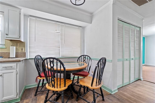 dining area featuring crown molding, baseboards, and wood finished floors