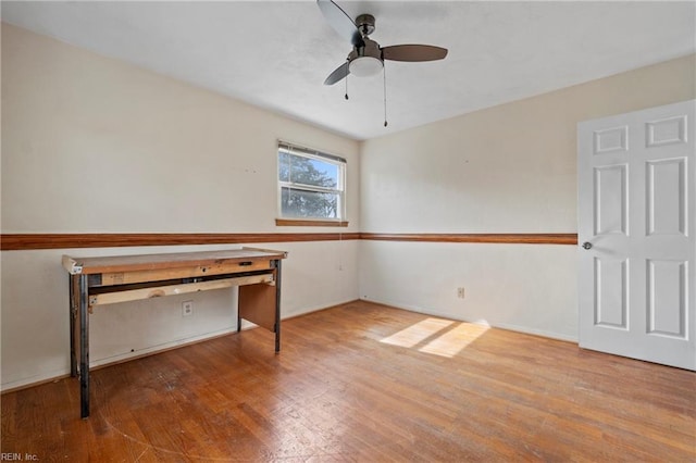 interior space with baseboards, wood-type flooring, and ceiling fan