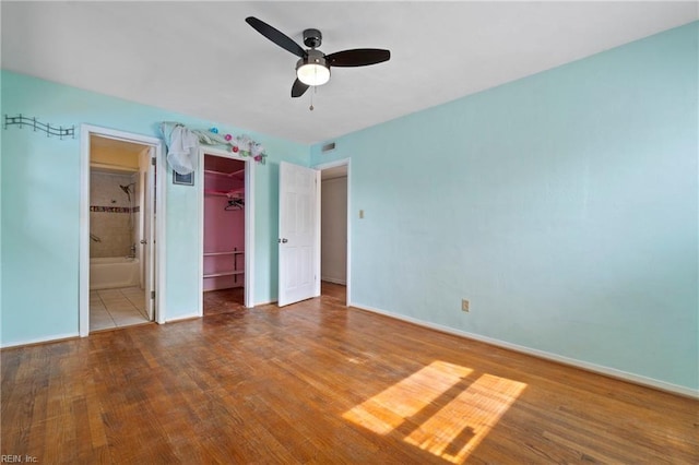 unfurnished bedroom with wood finished floors, baseboards, ceiling fan, a closet, and ensuite bathroom