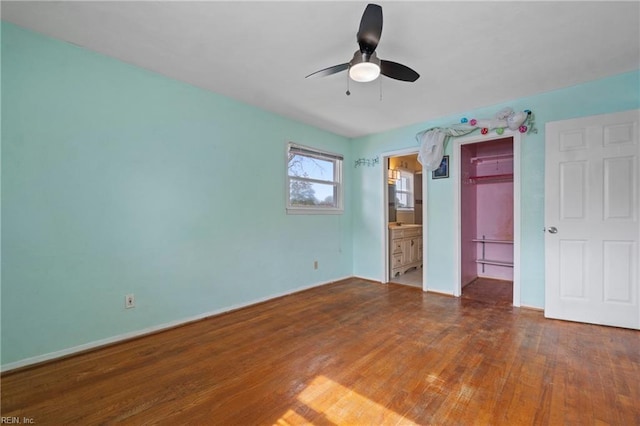 unfurnished bedroom with a closet, ensuite bathroom, a ceiling fan, and hardwood / wood-style floors