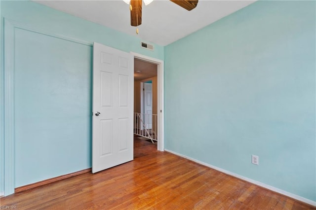 unfurnished bedroom with ceiling fan, visible vents, baseboards, and wood finished floors