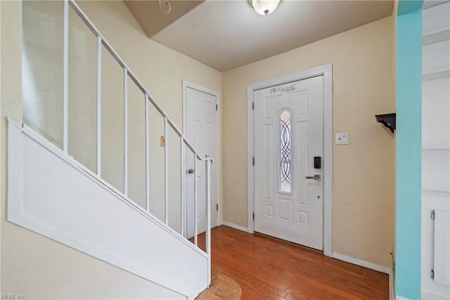 entryway with radiator, stairs, baseboards, and wood finished floors