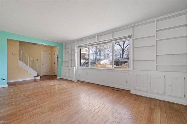 interior space with stairway, baseboards, and light wood finished floors