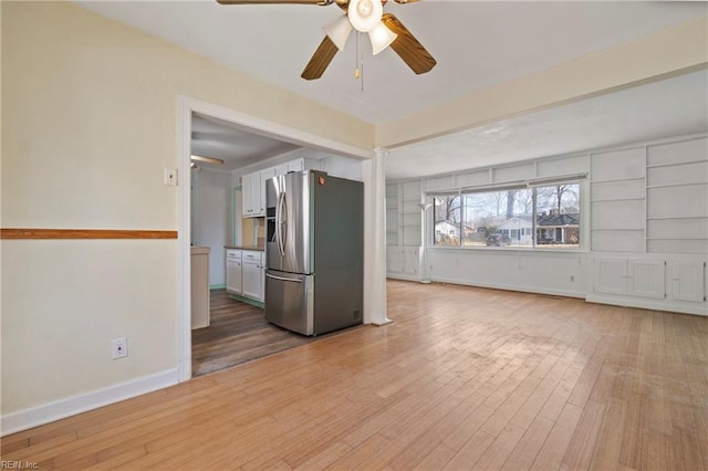 unfurnished living room featuring wood finished floors, baseboards, and ceiling fan