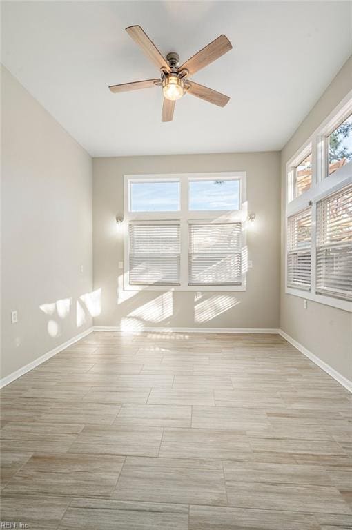 spare room with light wood-style flooring, a ceiling fan, and baseboards