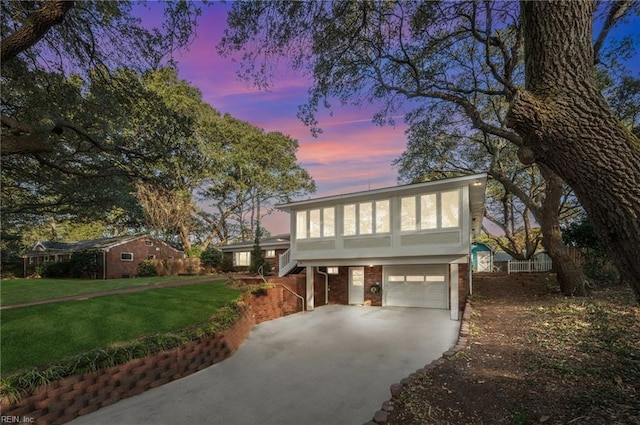 view of front of home featuring concrete driveway, a yard, brick siding, and a garage