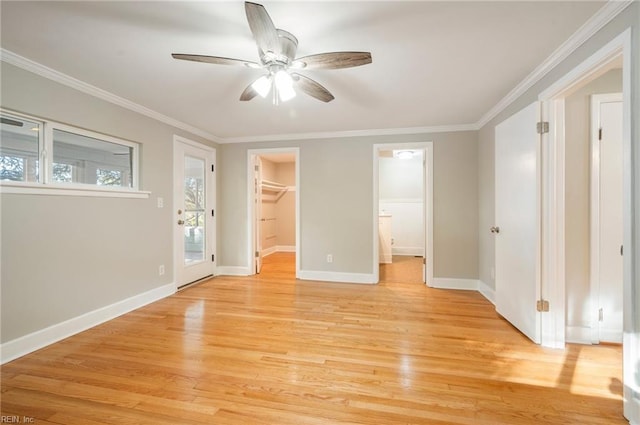 unfurnished bedroom featuring a spacious closet, crown molding, baseboards, light wood-style flooring, and a ceiling fan