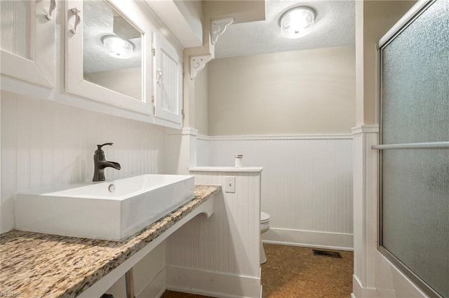 full bath with a wainscoted wall, visible vents, toilet, a textured ceiling, and vanity