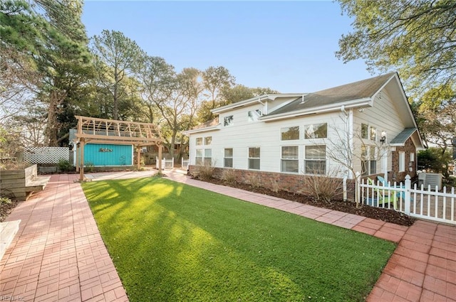 rear view of house with brick siding, a yard, and fence