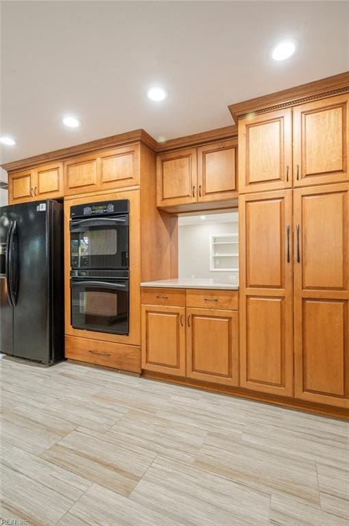 kitchen with black appliances, brown cabinetry, and light countertops