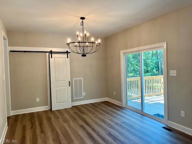 unfurnished dining area with dark wood-style floors, visible vents, a notable chandelier, and baseboards