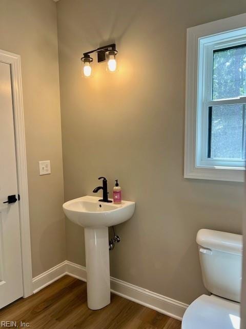 bathroom with toilet, baseboards, and wood finished floors