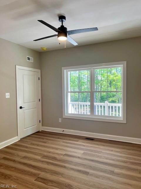 spare room featuring visible vents, wood finished floors, baseboards, and ceiling fan