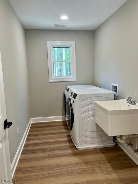 clothes washing area featuring laundry area, wood finished floors, separate washer and dryer, and visible vents