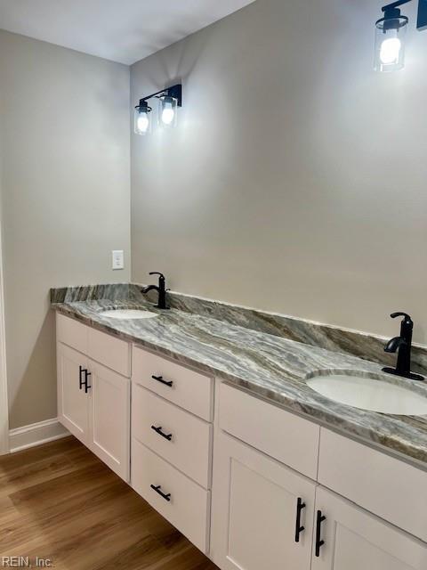 bathroom with double vanity, wood finished floors, and a sink