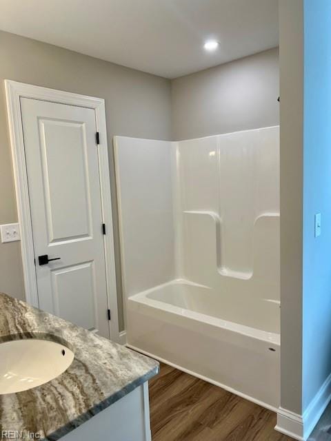 bathroom featuring vanity, washtub / shower combination, wood finished floors, and baseboards