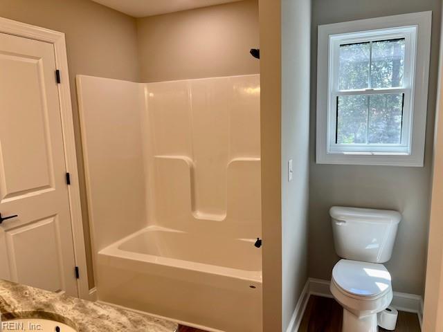 bathroom featuring baseboards, toilet, and shower / washtub combination