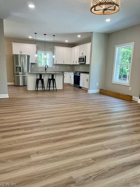 kitchen featuring a kitchen bar, appliances with stainless steel finishes, open floor plan, and white cabinetry