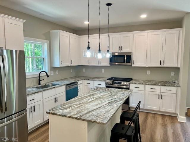 kitchen featuring white cabinetry, wood finished floors, appliances with stainless steel finishes, and a sink