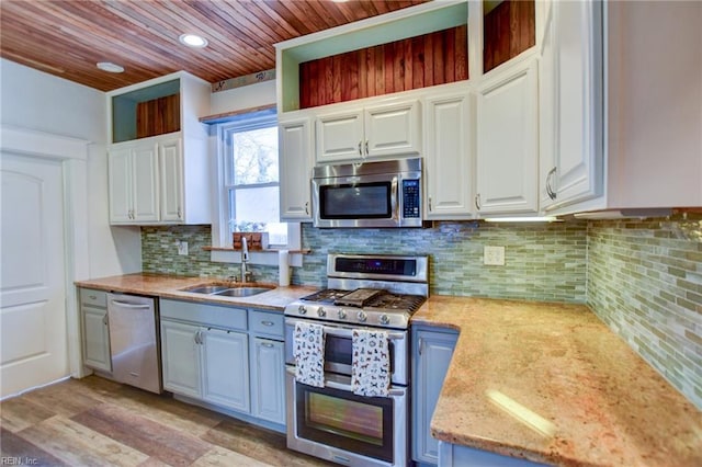 kitchen with a sink, backsplash, white cabinetry, appliances with stainless steel finishes, and wood ceiling