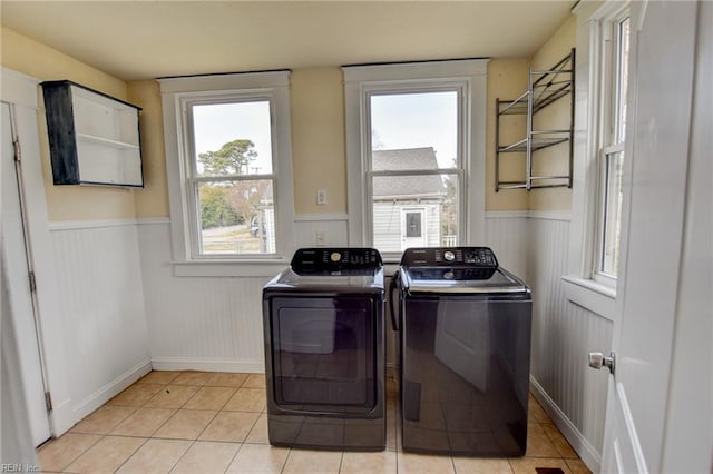 clothes washing area featuring laundry area, a healthy amount of sunlight, and a wainscoted wall