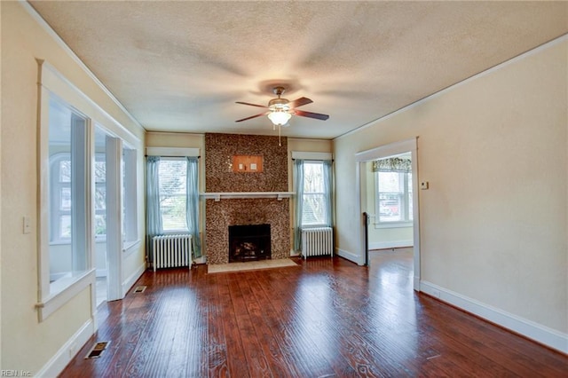 unfurnished living room with a premium fireplace, radiator, wood finished floors, and a textured ceiling