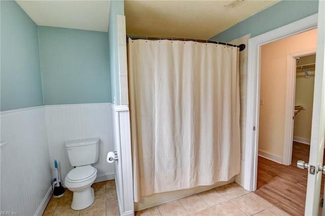 full bathroom featuring visible vents, wainscoting, curtained shower, tile patterned floors, and toilet