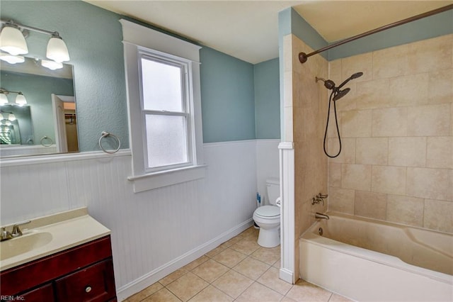 bathroom with tile patterned floors, a wainscoted wall, toilet, bathtub / shower combination, and vanity