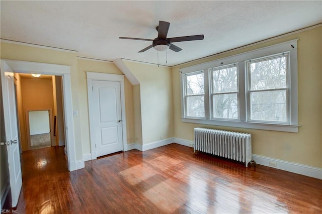 unfurnished bedroom with wood finished floors, baseboards, radiator heating unit, a textured ceiling, and crown molding