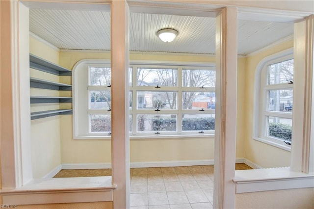 interior space featuring tile patterned floors, baseboards, and ornamental molding