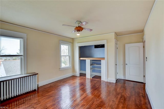 interior space featuring a closet, radiator heating unit, baseboards, and wood finished floors