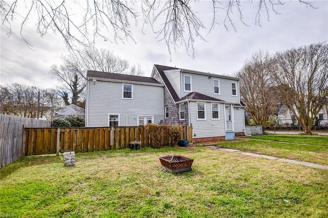 back of house with a yard, a fire pit, and a fenced backyard