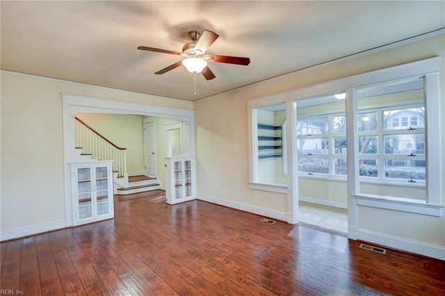 unfurnished room with visible vents, a ceiling fan, wood-type flooring, baseboards, and stairs