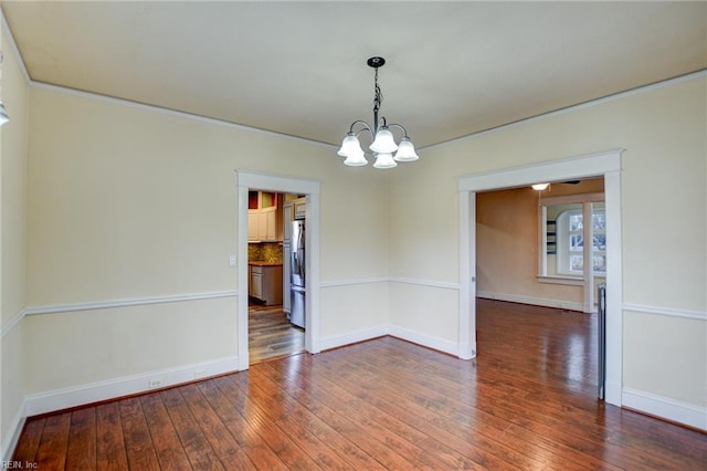 empty room with baseboards, wood-type flooring, and a notable chandelier