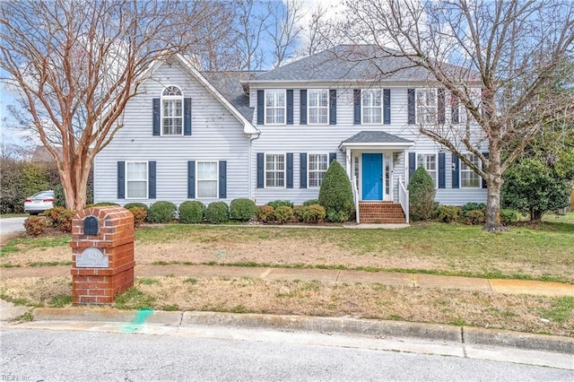 colonial home with a front lawn and roof with shingles