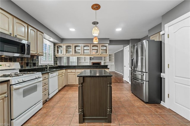 kitchen with a kitchen island, glass insert cabinets, appliances with stainless steel finishes, dark countertops, and tile patterned floors