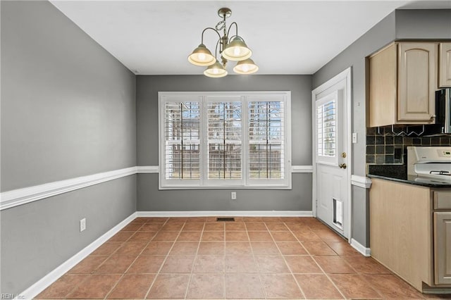 unfurnished dining area featuring light tile patterned floors, a chandelier, and baseboards