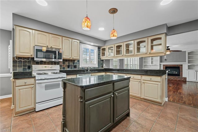 kitchen with a ceiling fan, stainless steel microwave, a peninsula, glass insert cabinets, and white gas range