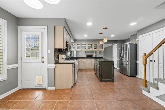 kitchen featuring dark countertops, glass insert cabinets, baseboards, light tile patterned floors, and stainless steel appliances