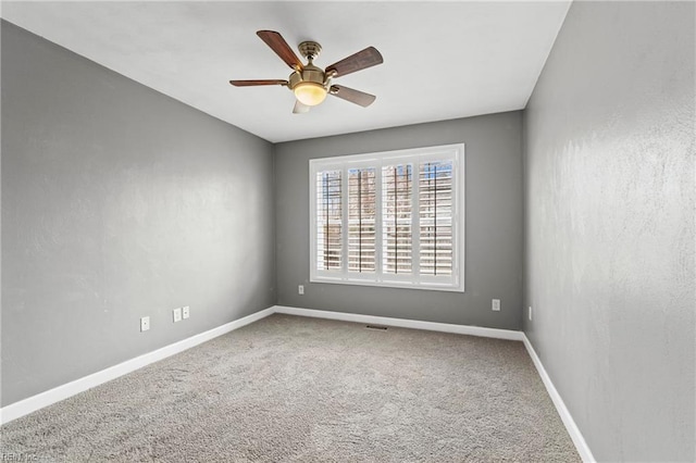 carpeted empty room featuring visible vents, baseboards, and ceiling fan