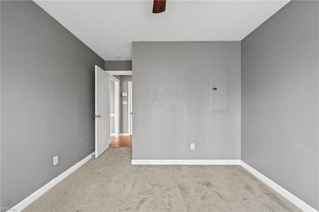 carpeted spare room featuring electric panel and baseboards