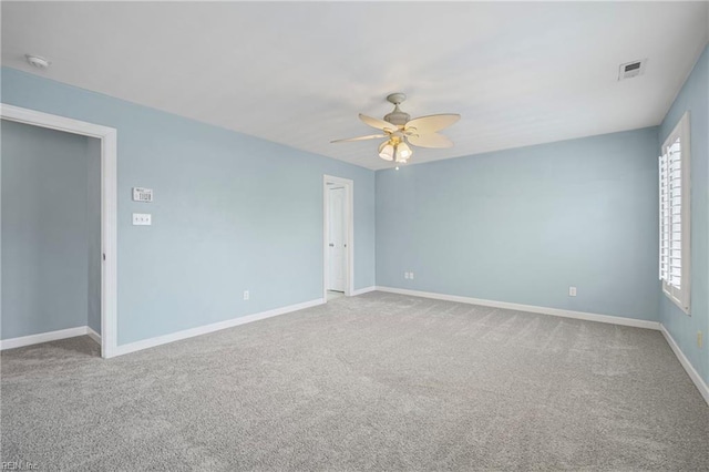 carpeted empty room with visible vents, baseboards, and ceiling fan