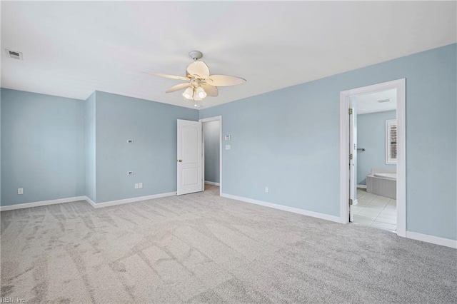 unfurnished bedroom featuring visible vents, ensuite bath, carpet floors, baseboards, and ceiling fan