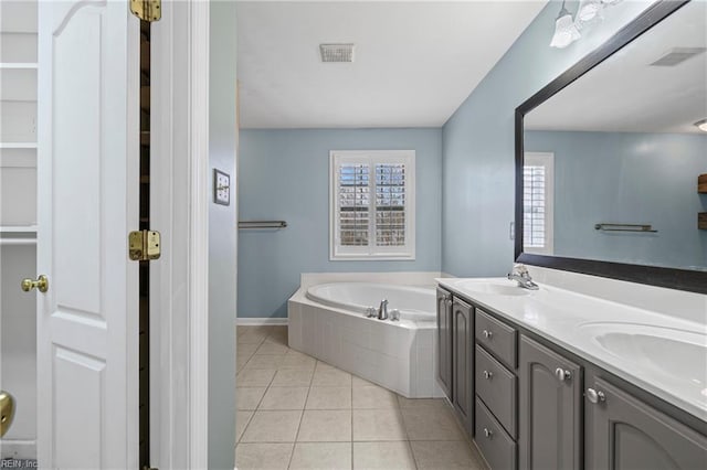 bathroom featuring tile patterned floors, a garden tub, visible vents, and a sink