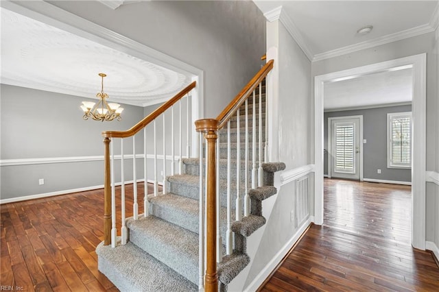 staircase featuring visible vents, a notable chandelier, ornamental molding, hardwood / wood-style floors, and baseboards