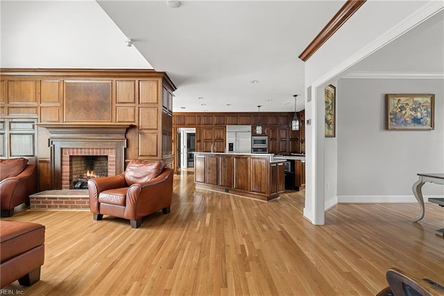 living room featuring light wood-style flooring, baseboards, ornamental molding, and a fireplace