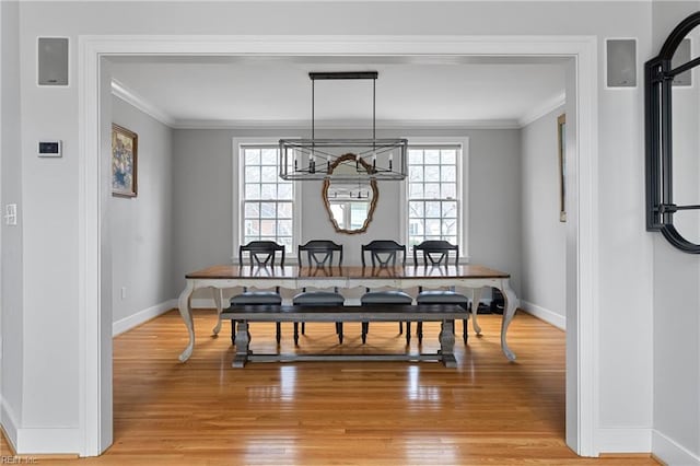 dining area featuring an inviting chandelier, baseboards, light wood finished floors, and ornamental molding