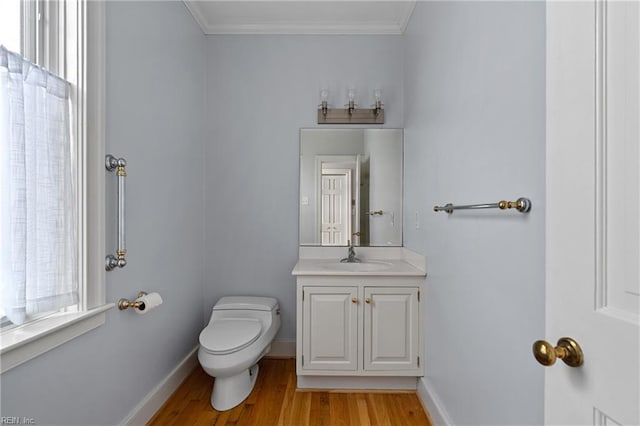 bathroom featuring crown molding, baseboards, toilet, wood finished floors, and vanity