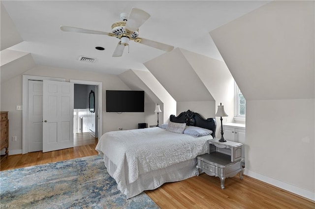 bedroom with visible vents, light wood-style flooring, baseboards, and lofted ceiling