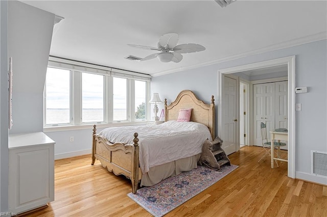 bedroom featuring visible vents, crown molding, and light wood finished floors